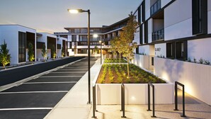 A modern building with a parking lot, a landscaped area with trees, and a street lamp. - Clayton Serviced Apartments (Clayton)