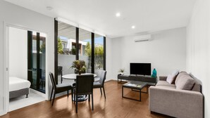 A modern living room with a sofa, TV, and dining area. - Clayton Serviced Apartments (Clayton)