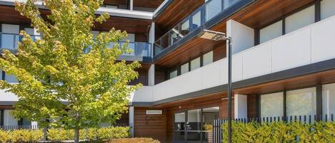 Un bâtiment moderne doté d’un espace d’accueil, de plusieurs étages et d’un arbre au premier plan.