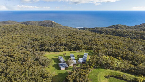 A remote, eco-friendly resort with solar-powered buildings amidst lush greenery, overlooking a vast ocean. - Alkina Lodge (Wattle Hill)