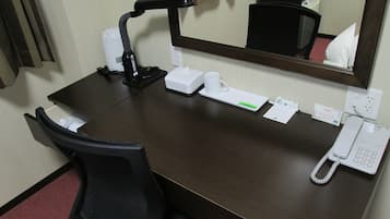 Balcão de hotel com telefone, caixa de lenços, chávena e espelho.