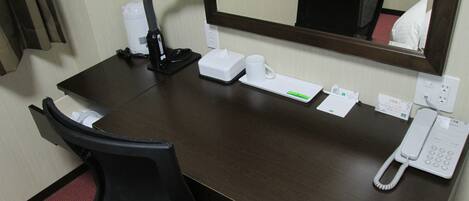 Un bureau d’hôtel avec un téléphone, une boîte de mouchoirs, une tasse et un miroir.