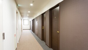 Un largo pasillo con puertas a un lado y una ventana al final.