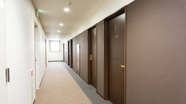 A long corridor with doors on one side and a window at the end. - Okawa Riverside Hotel (Okawa)