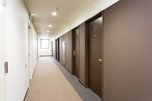 Un largo pasillo con puertas a un lado y una ventana al final.