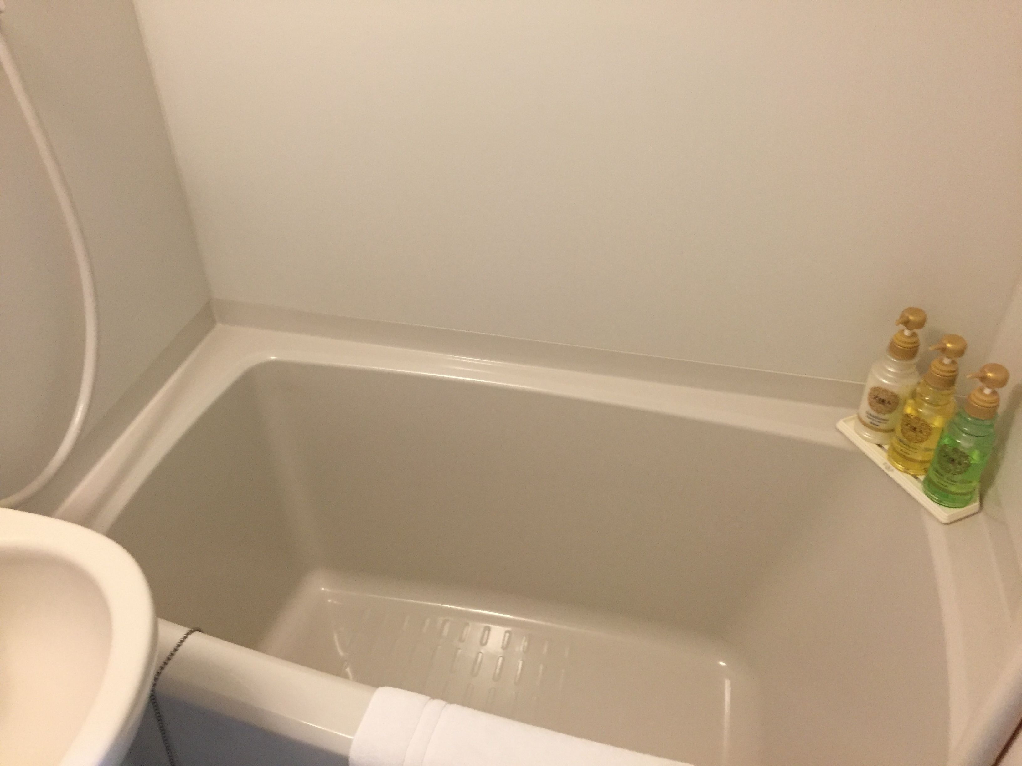 A bathroom with a bathtub, a toilet, and a shelf with toiletries.