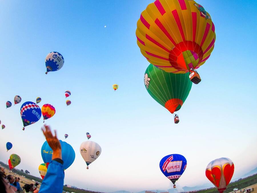 A hot air balloon festival with various colorful balloons in the sky.