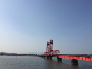 A red bridge over a body of water with a clear sky. - Okawa Riverside Hotel (Okawa)