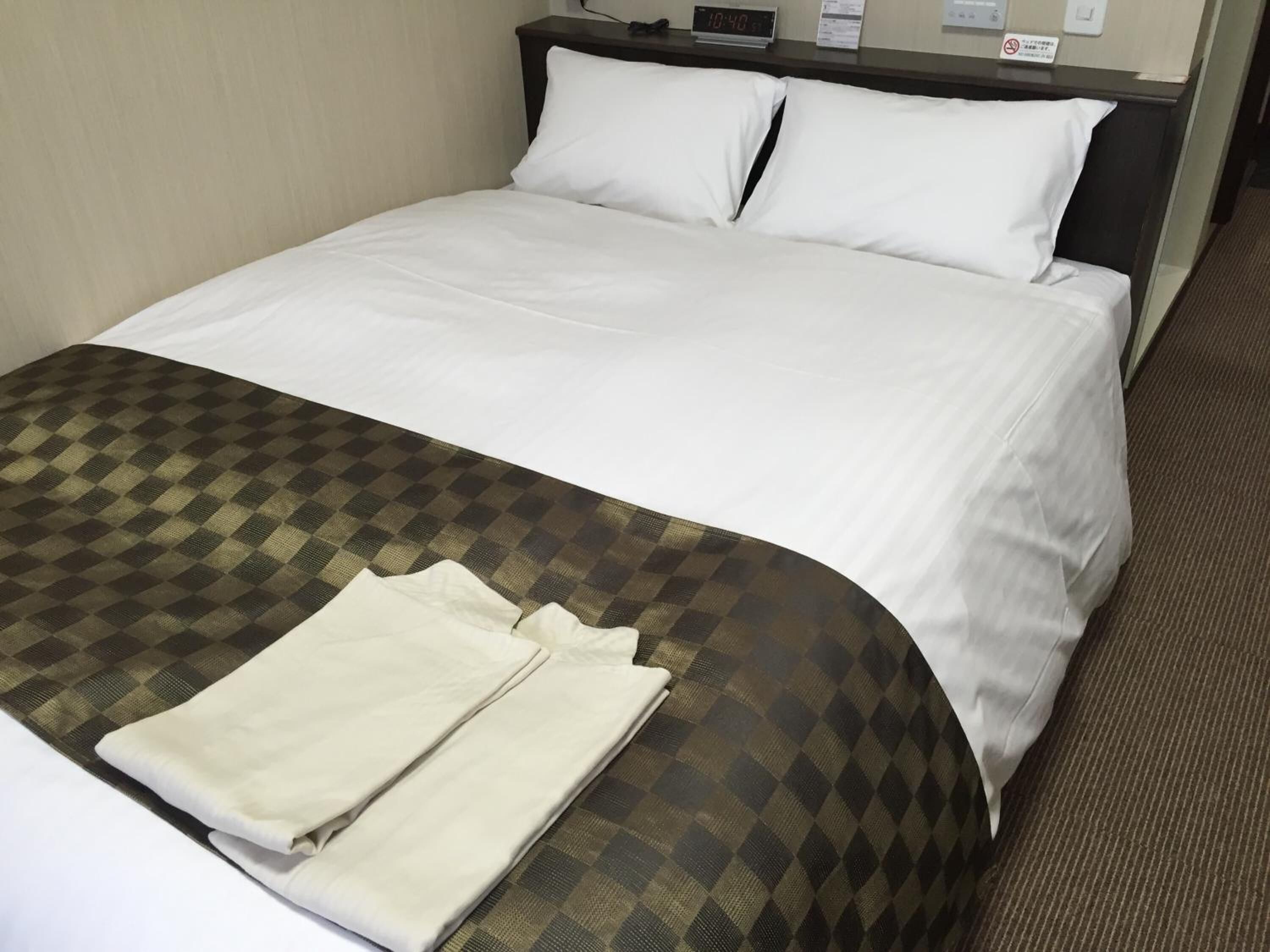 A neatly made bed with white linens and a checkered blanket.