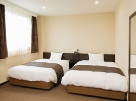 Habitación de hotel con dos camas individuales, una mesita de noche y un ventanal con cortinas.