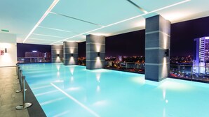 Una piscina interior moderna con vistas a la ciudad, con iluminación geométrica y un diseño limpio y contemporáneo.