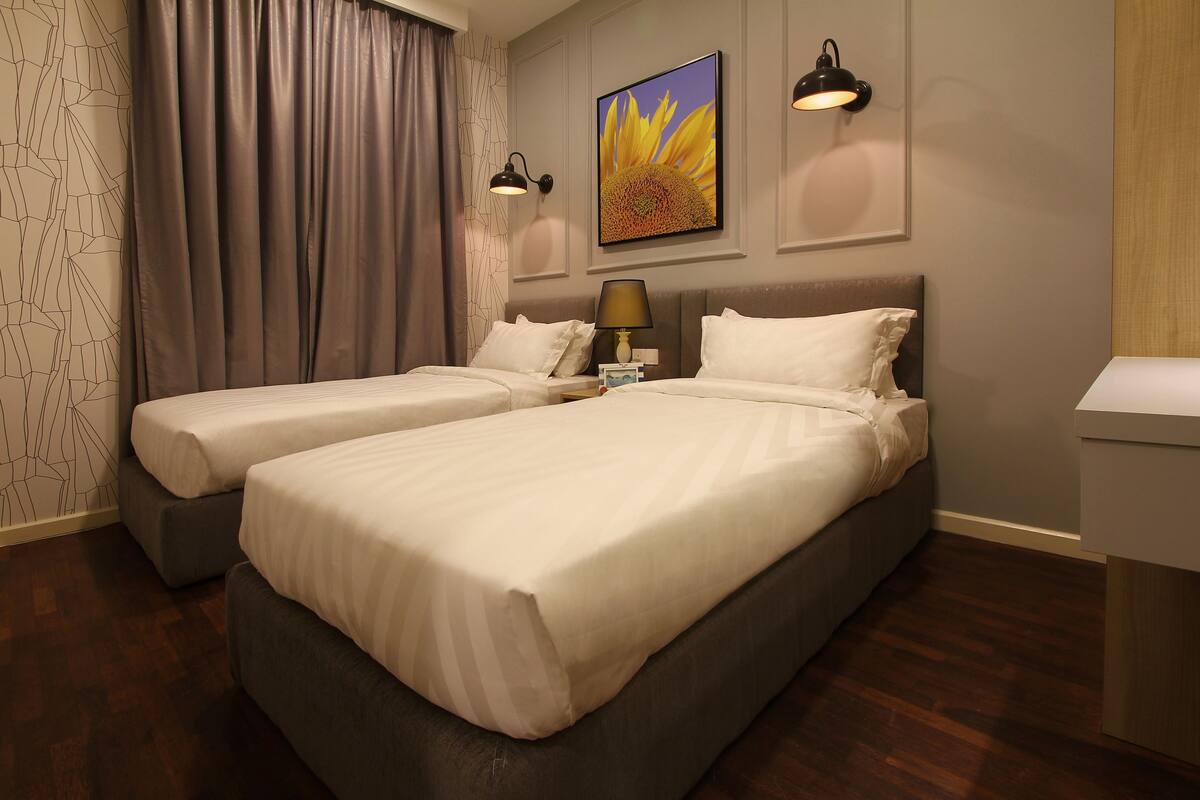 Une chambre d’hôtel avec deux lits, une table de chevet, une lampe, un tableau et un mur décoré de motifs.