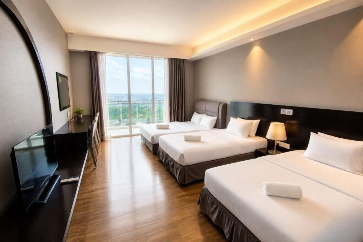 A hotel room with two beds, a TV, a desk, and a view of the outdoors.