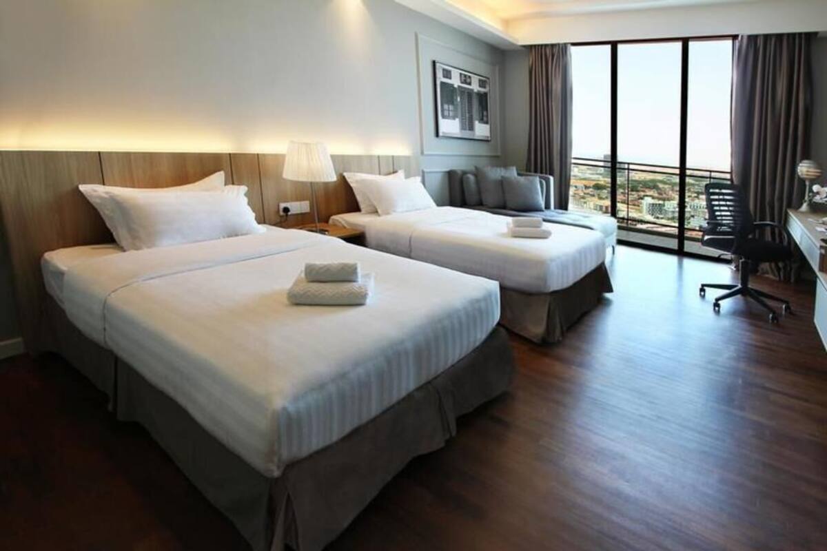Une chambre d’hôtel avec deux lits, un bureau et une grande fenêtre donnant sur un beau paysage.