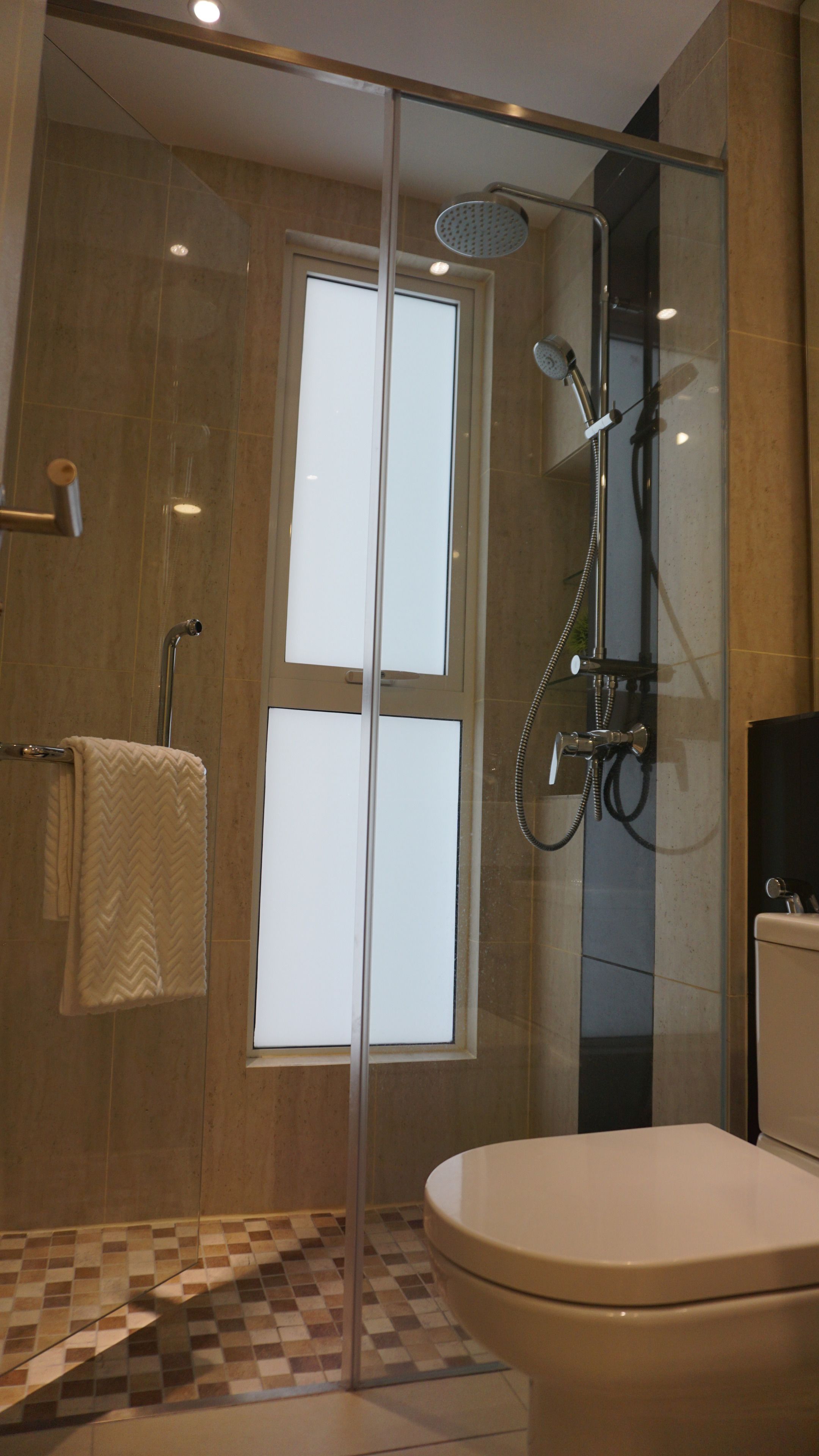 Un baño moderno con ducha de vidrio, inodoro y toallero.
