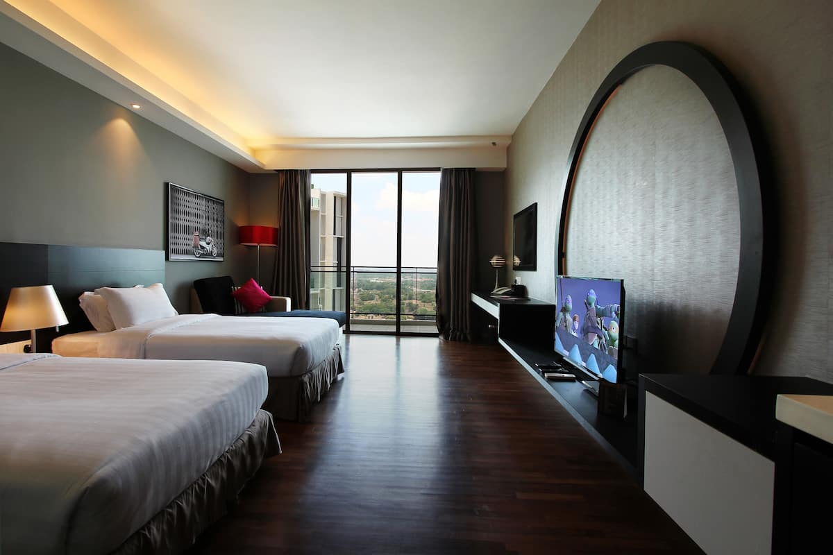 Une chambre d’hôtel avec deux lits, une télévision, un bureau et une grande fenêtre donnant sur un beau paysage.