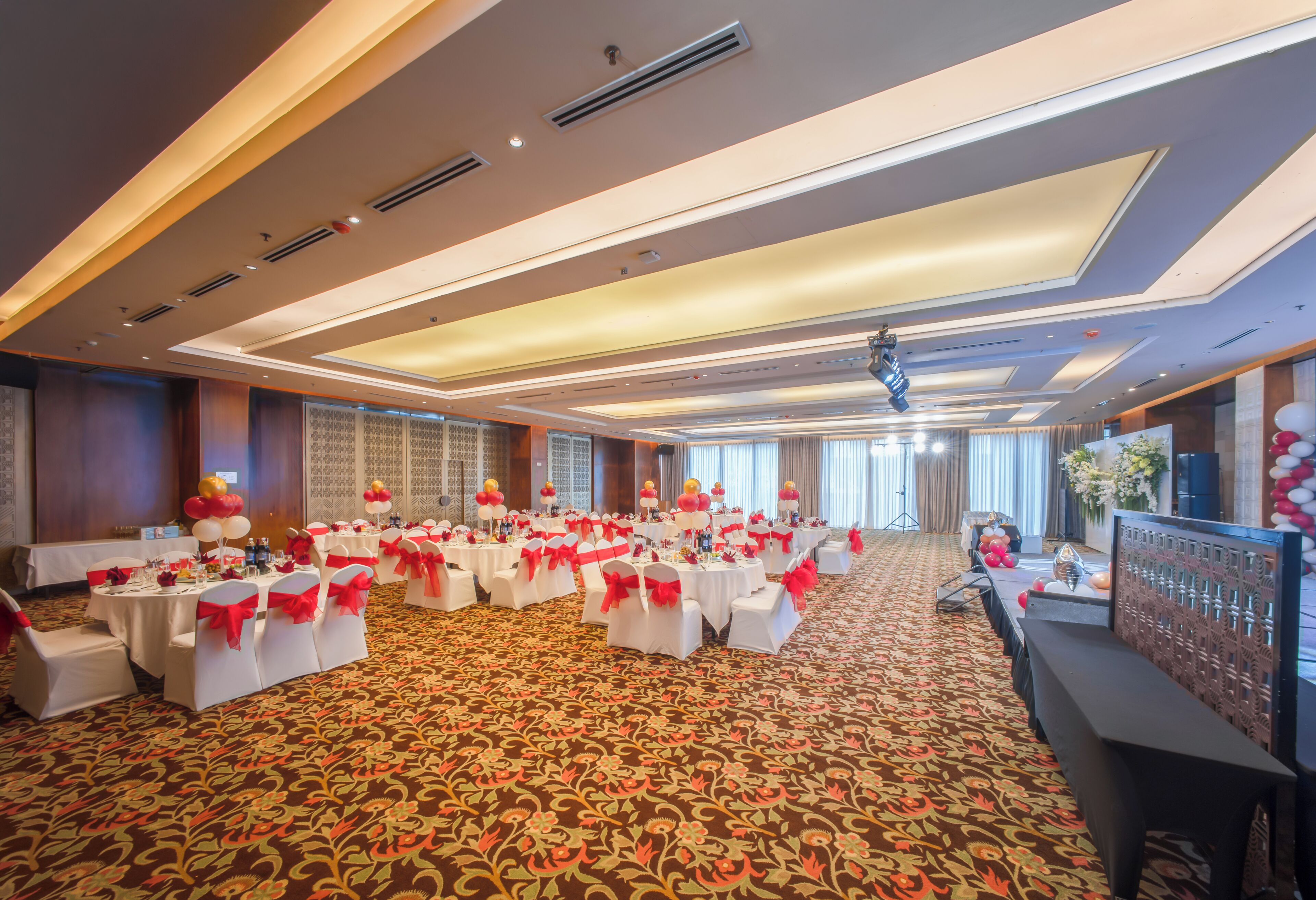 A banquet hall with round tables, white tablecloths, and red sashes.