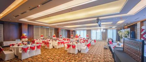 A banquet hall with round tables, white tablecloths, and red sashes.