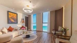 Een moderne woonkamer met een bank, fauteuils, een salontafel en uitzicht op de oceaan.