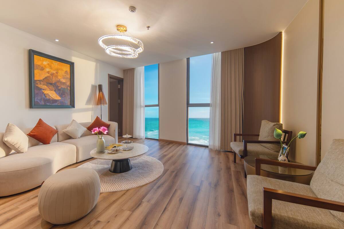 Un salon moderne avec un canapé, des fauteuils, une table basse et une vue sur l’océan.