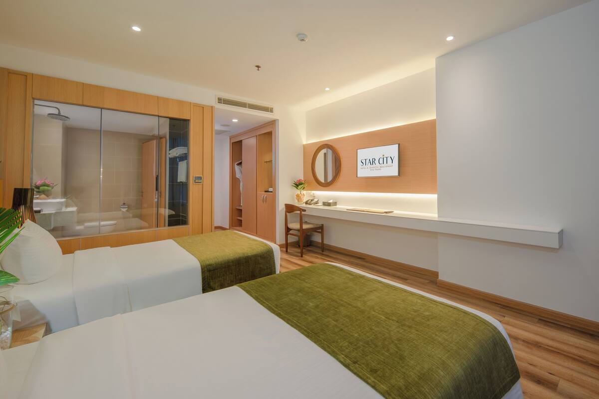 Une chambre d’hôtel avec deux lits, un bureau, un miroir et un espace douche.