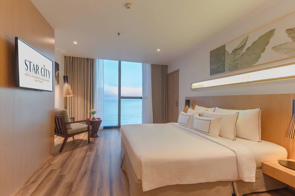 Une chambre d’hôtel avec un grand lit, un bureau, une chaise et une vue sur la mer.