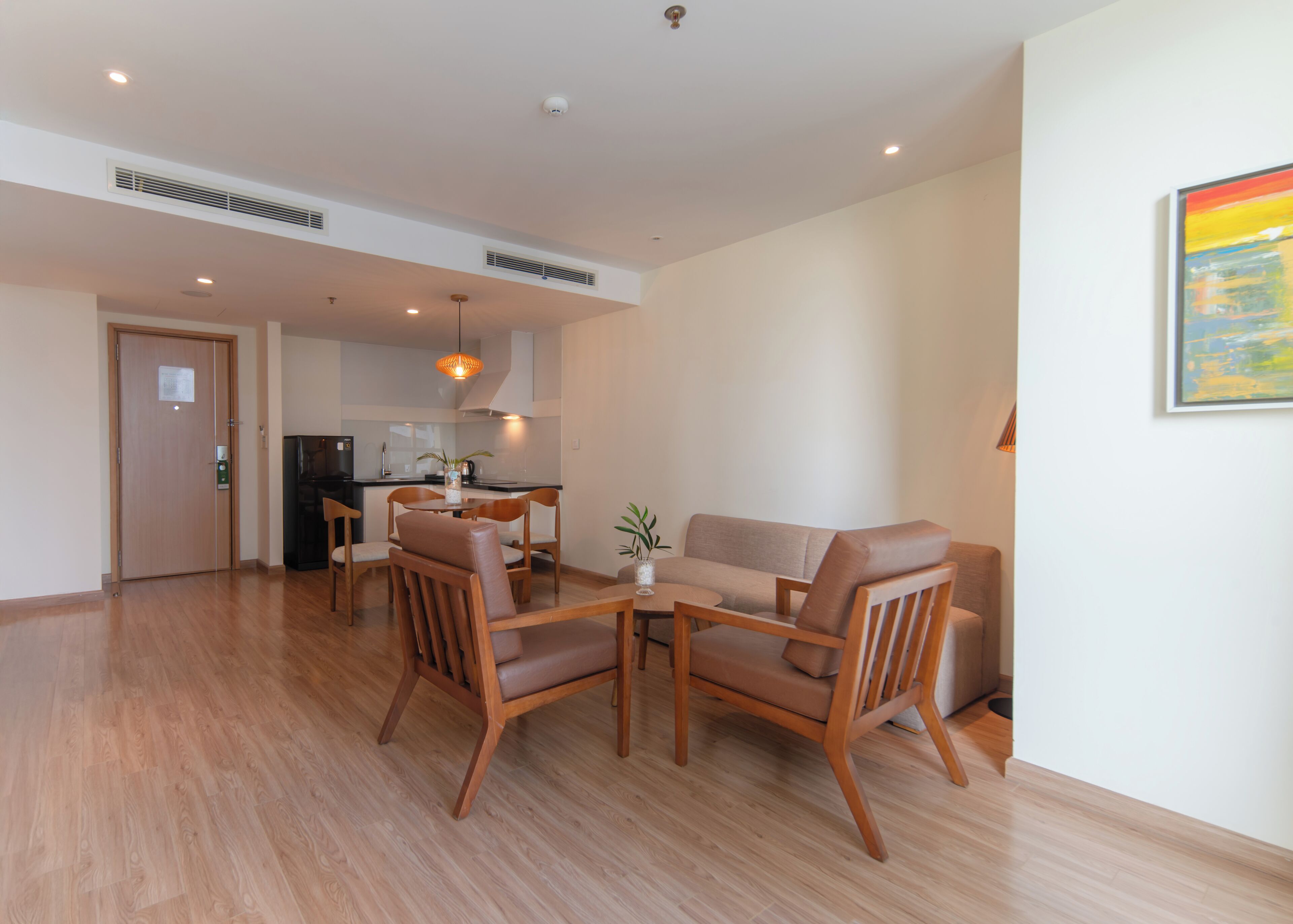 A modern living room with a dining area, wooden flooring, and a kitchen in the background.