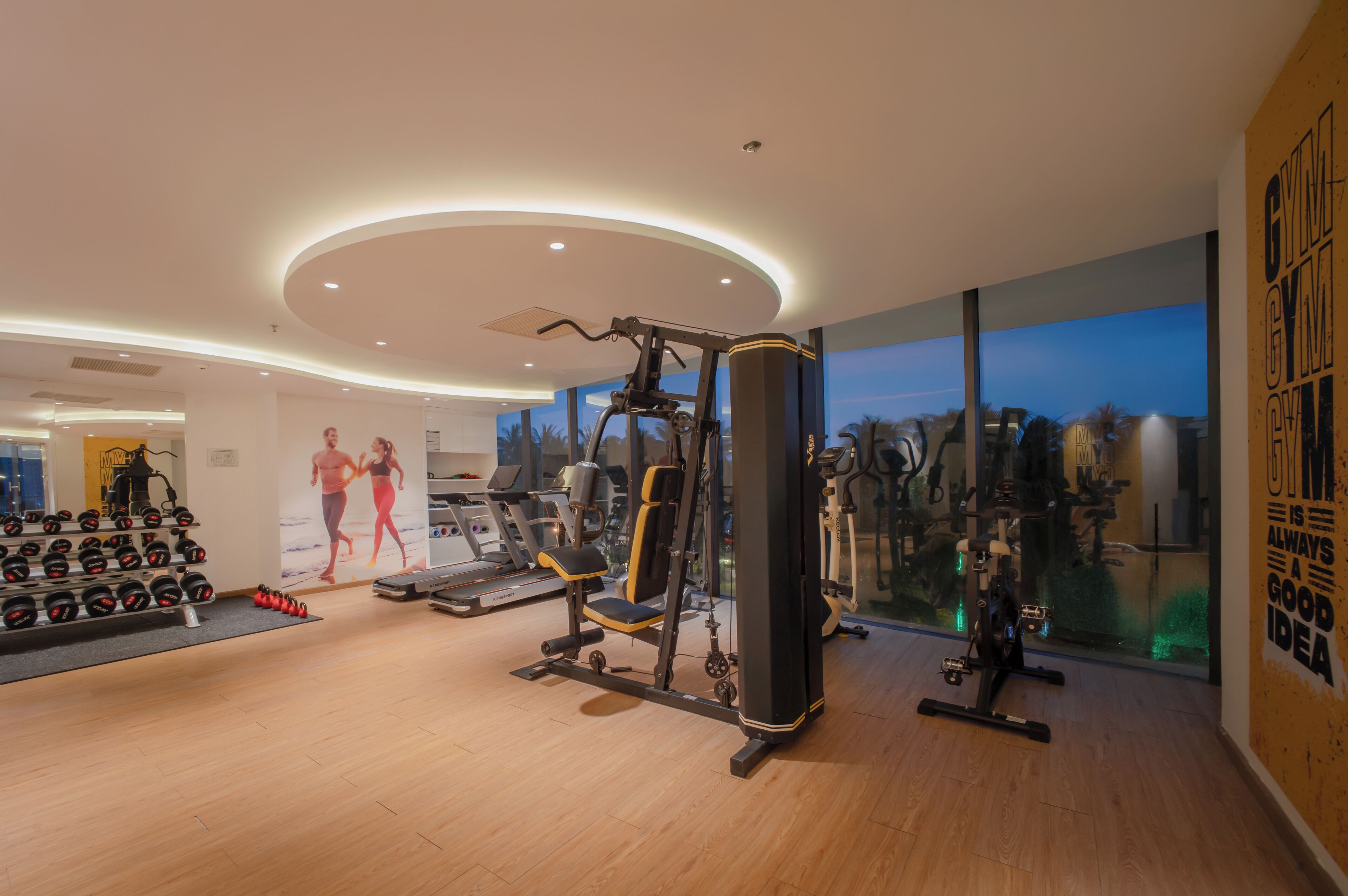 A modern gym with cardio machines, weightlifting equipment, and a large mirror.