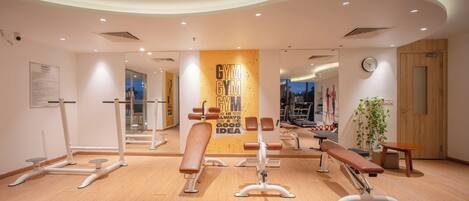 Un gimnasio moderno con equipamiento de ejercicio, un cartel motivacional y suelo de madera.