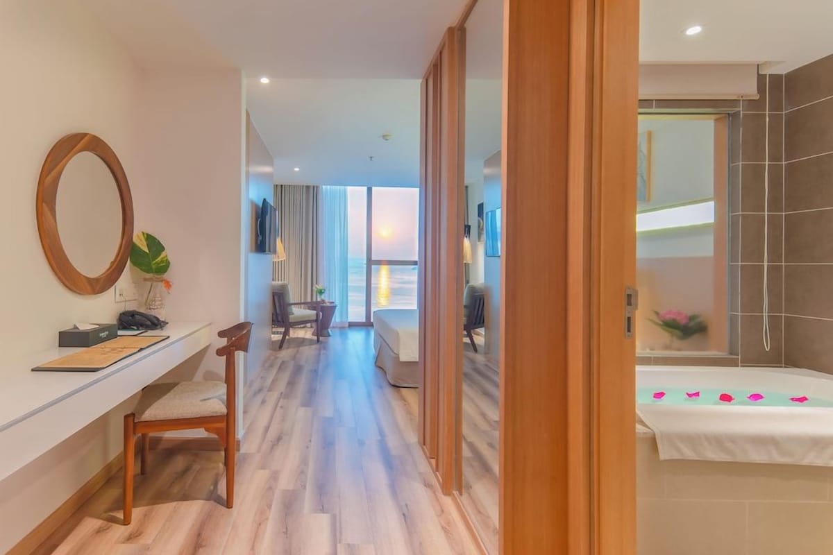 Een hotelkamer met een houten bureau, een stoel, een bed en een badkamer met douche.