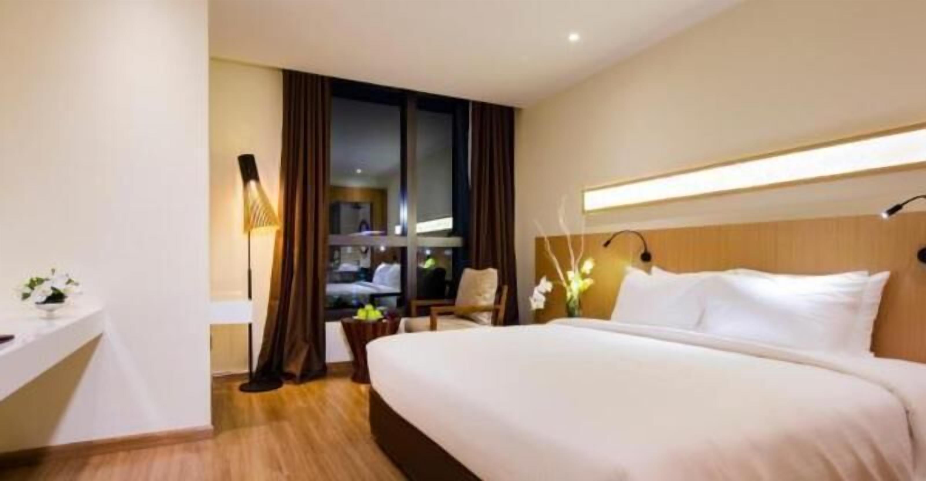 Une chambre d’hôtel avec un grand lit, un bureau, une chaise et une fenêtre avec des rideaux.