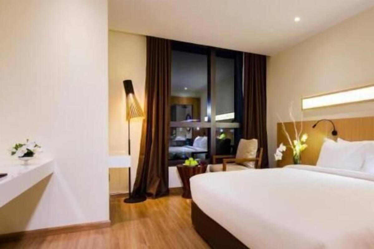 Ein Hotelzimmer mit einem großen Bett, einem Schreibtisch, einem Stuhl und einem Vorhangfenster.