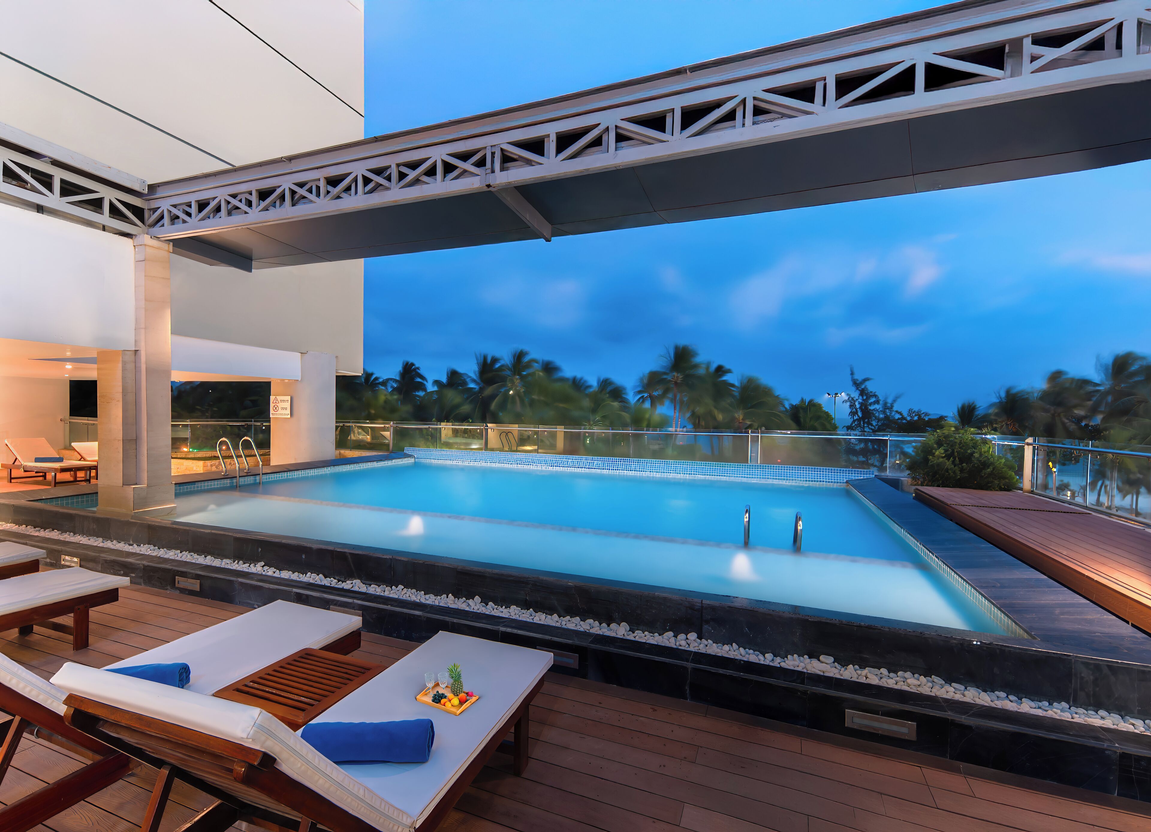 A rooftop pool with lounge chairs and a wooden deck.