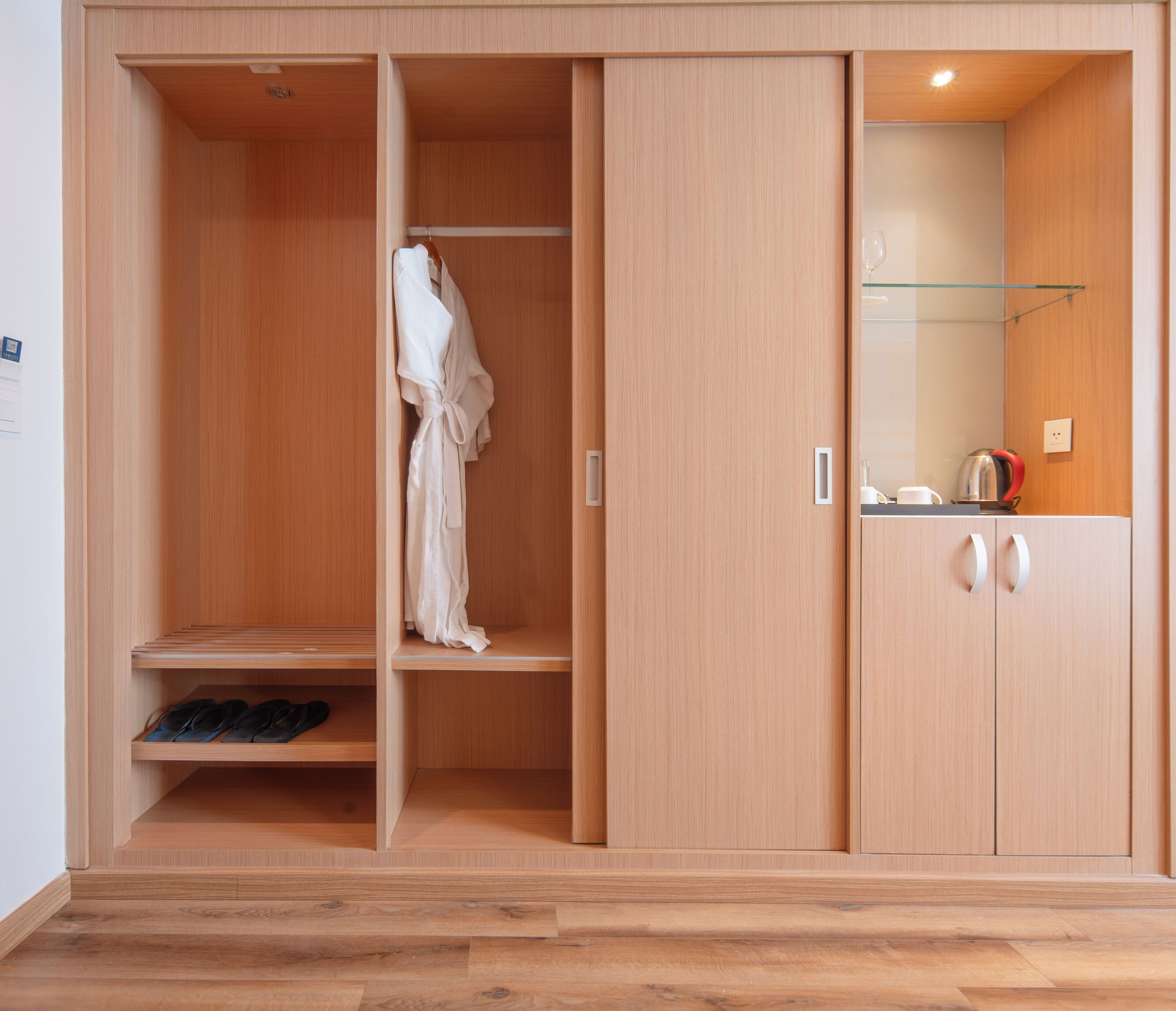 A wooden wardrobe with multiple compartments, including a hanging section and shelves.