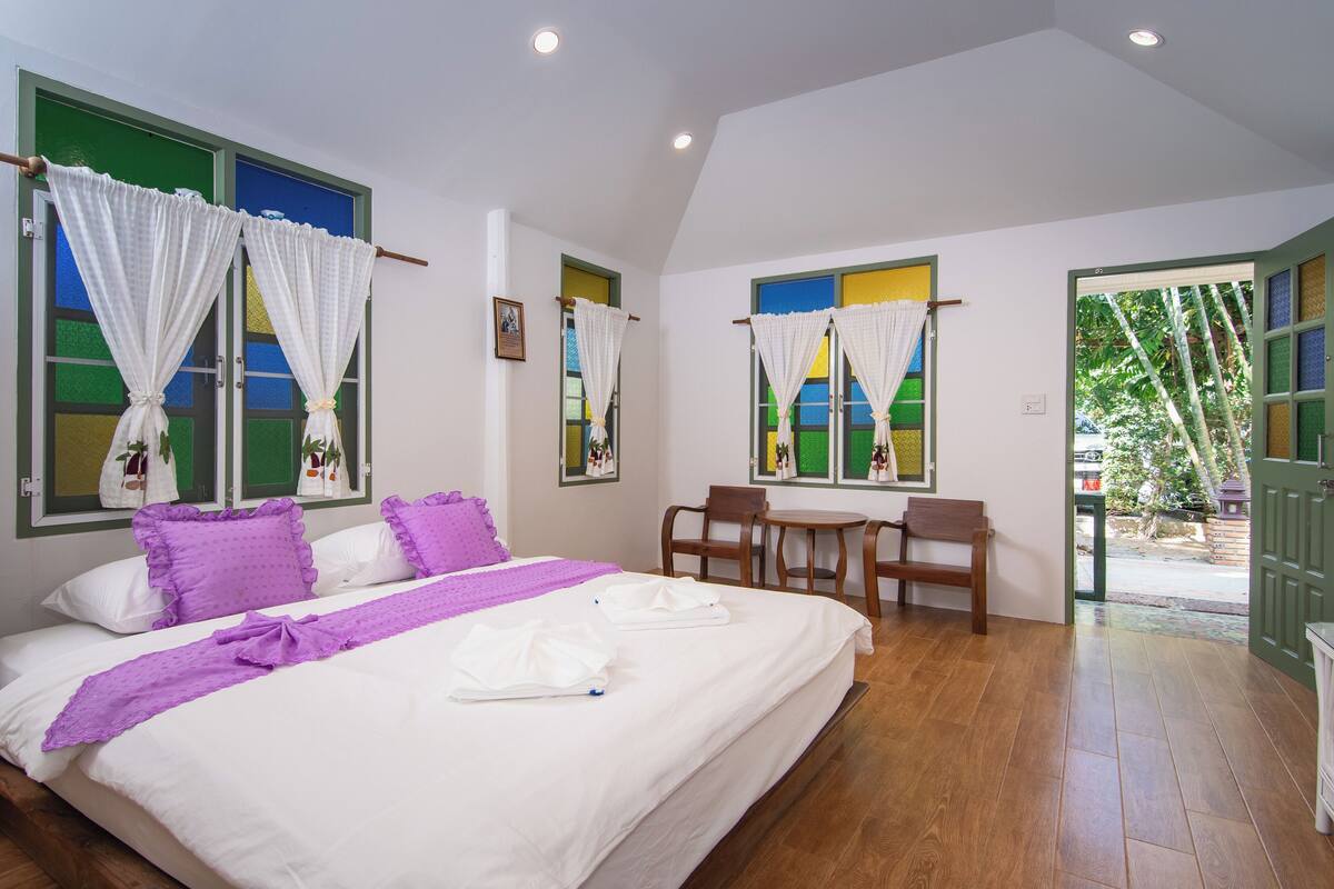 Une chambre d’hôtel avec un lit, un bureau, des chaises et une vue sur l’extérieur.