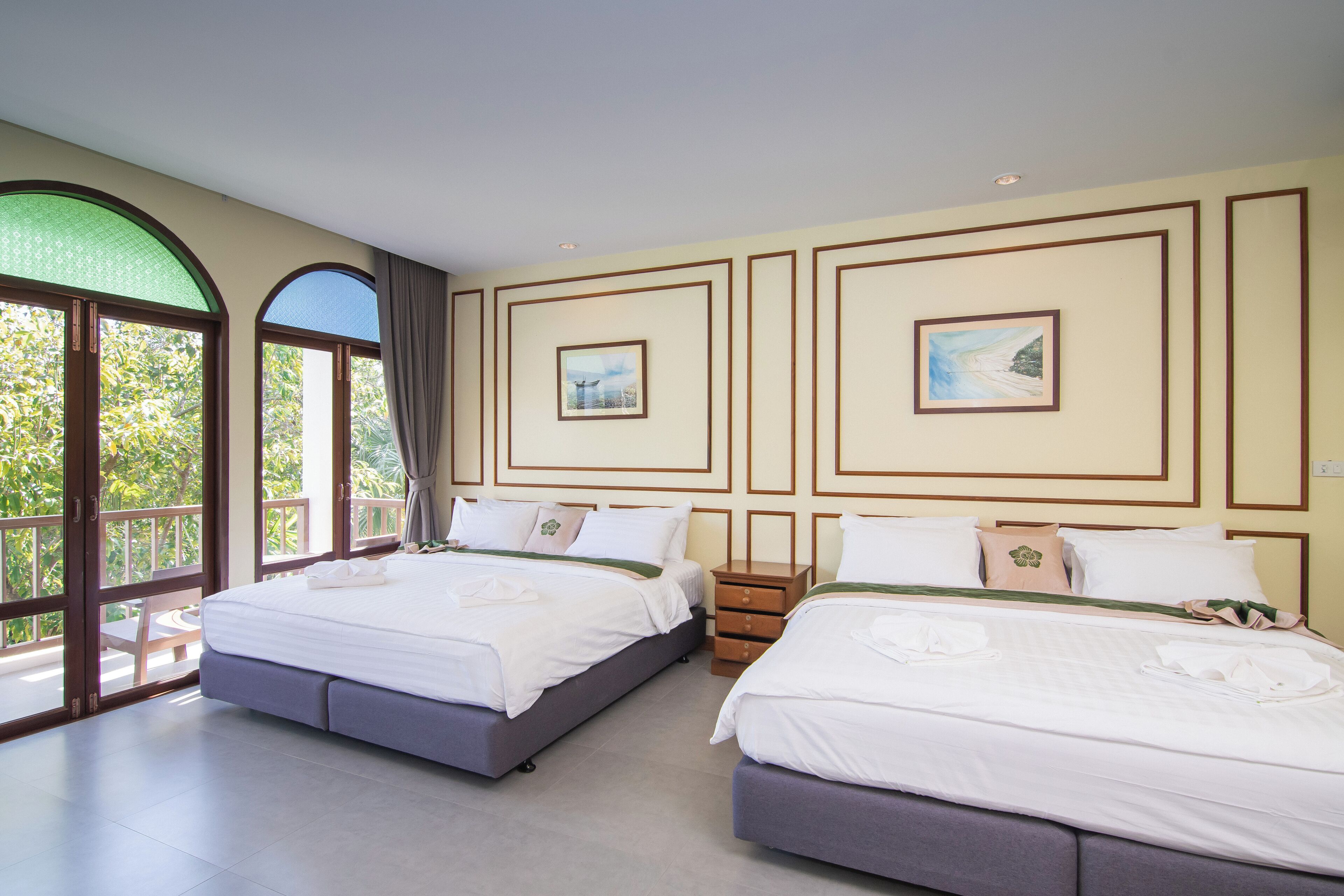 A hotel room with two beds, large windows, and artwork on the walls.