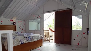 A bedroom with a wooden bed, a chair, and a hammock. - Villa Bintang (Gili Trawangan)