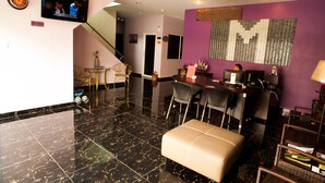 A hotel lobby with a black marble floor, a bar area with a purple accent wall, and a television mounted on the wall. - Micasa Hotel (Labuan)