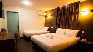 A hotel room with two beds, a desk, a chair, an air conditioning unit, and a telephone on a bedside table. - Micasa Hotel (Labuan)