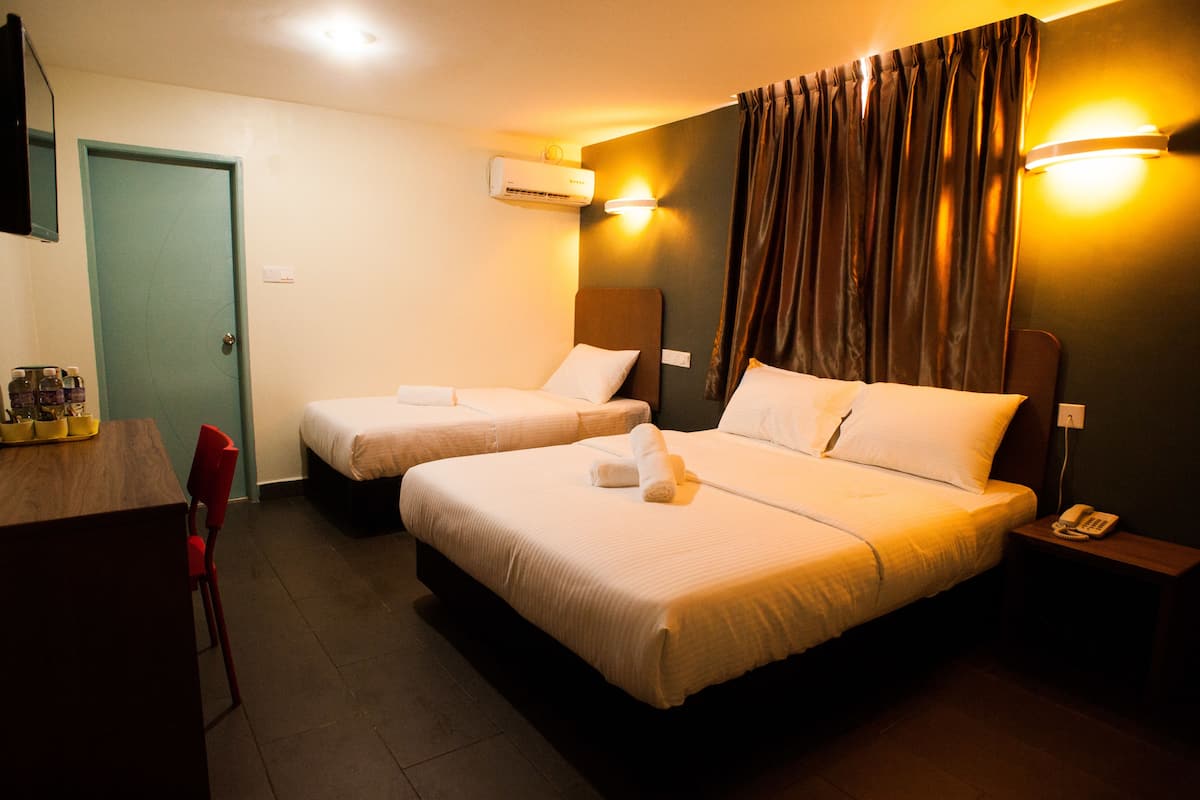 A hotel room with two beds, a desk, a chair, an air conditioning unit, and a telephone on a bedside table.