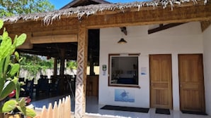 A building with a thatched roof, a wooden door, and a window. - Alona Pawikan (Panglao)