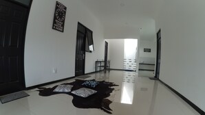 A spacious hallway with a polished floor, a black door, and a wall-mounted clock. - Mess Inn Semarang (Semarang)