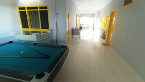 A pool table in a room with a long corridor leading to a seating area. - Mess Inn Semarang (Semarang)