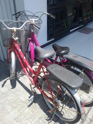 En röd cykel med en korg och ett sadel, parkerad på en asfalterad yta.