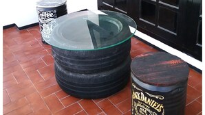 A set of stacked tires with a glass top, a trash can, and a barrel with text. - Mess Inn Semarang (Semarang)
