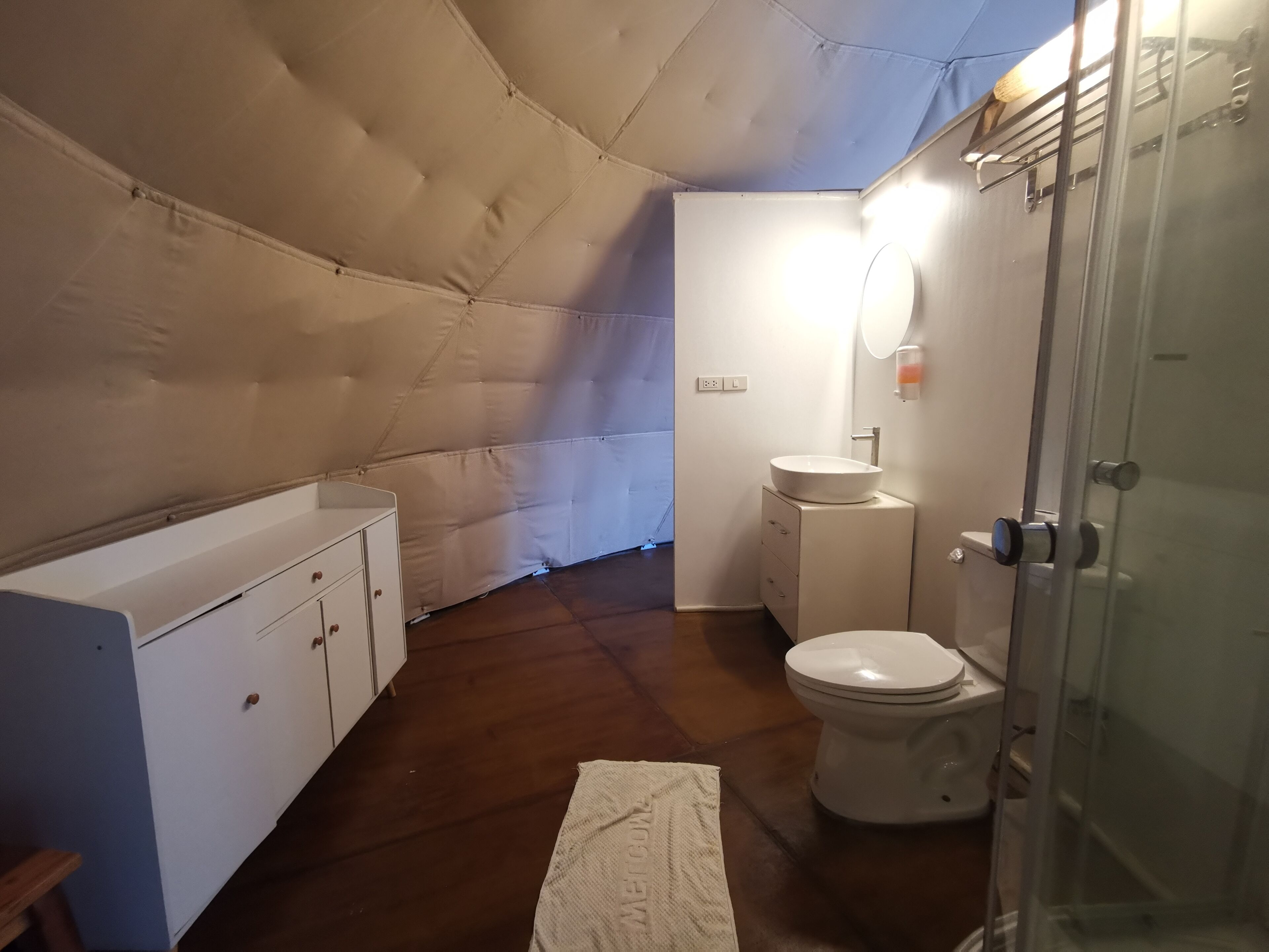 A compact, modern bathroom with a white bathtub, a toilet, and a glass shower enclosure.