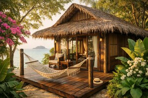 A wooden bungalow with a thatched roof, a hammock, and a view of the sea. - Eco Lanta Hideaway Beach Resort (Ko Lanta)