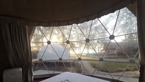 A room with a large window, a bed with neatly folded towels, and a view of a tent and trees outside. - Eco Lanta Hideaway Beach Resort (Ko Lanta)