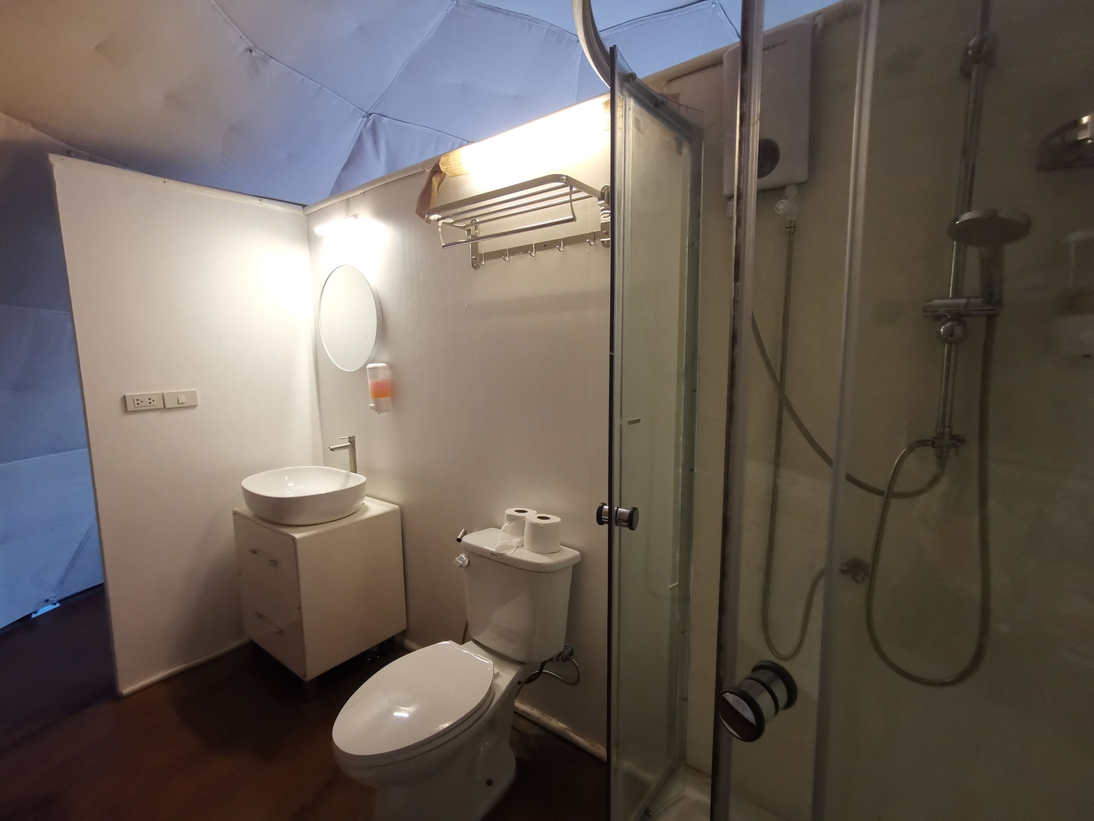 A compact bathroom with a toilet, sink, and glass-enclosed shower.