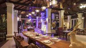 A dining area with a long wooden table set for a meal, surrounded by wooden chairs. - Fanli Resort Chiang Mai (Mae Rim)